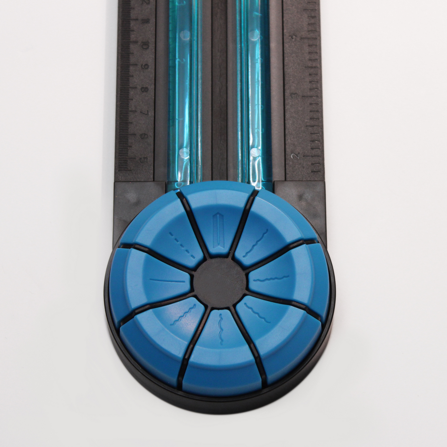 Close-up of the blue dial of an A4 Dial-A-Blade Creative Trimmer, set against the trimmer's ruler for scale, highlighting the selector that allows users to switch between the trimmer's multiple cutting functions.
