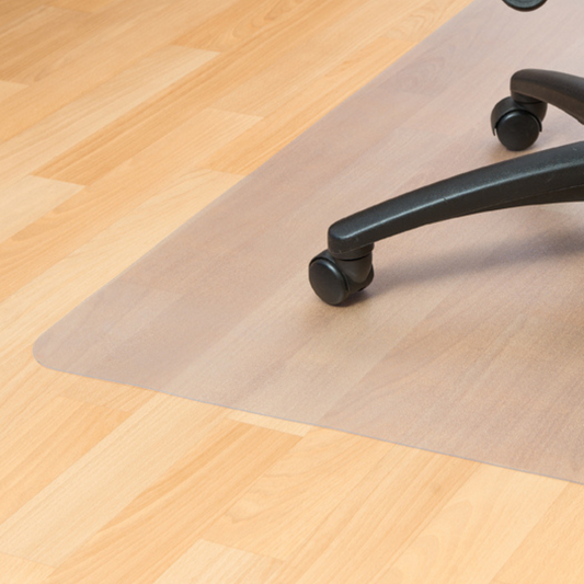 A clear PVC floor mat measuring 90x120cm, placed on a wooden floor under the black wheels of an office chair, designed to protect hard floors from wear and tear caused by rolling chairs.