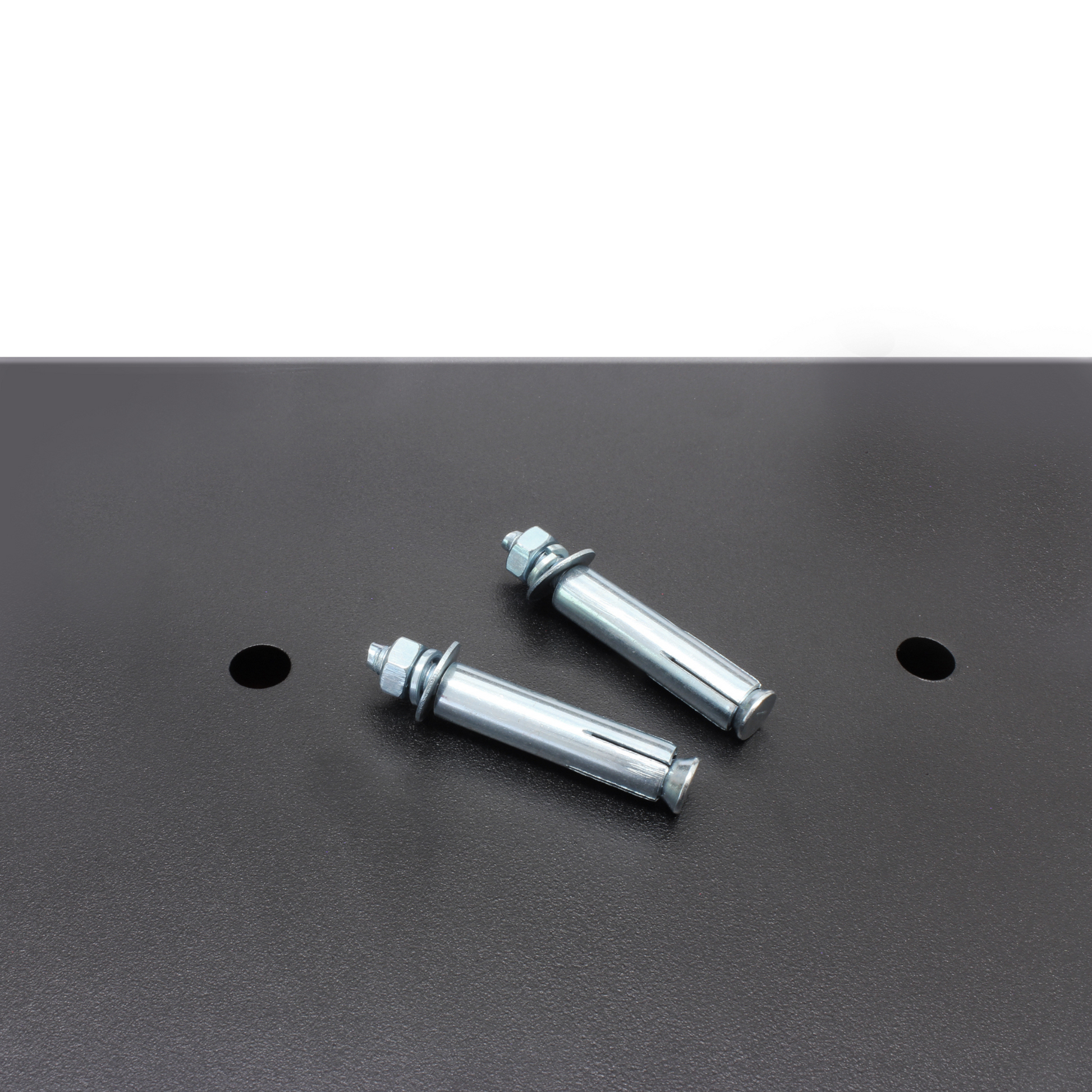 Two metal bolts rest on the black surface of the surface of the Cathedral Products EA25 16 Litre Electronic Digital Safe, next to pre-drilled mounting holes for secure installation.