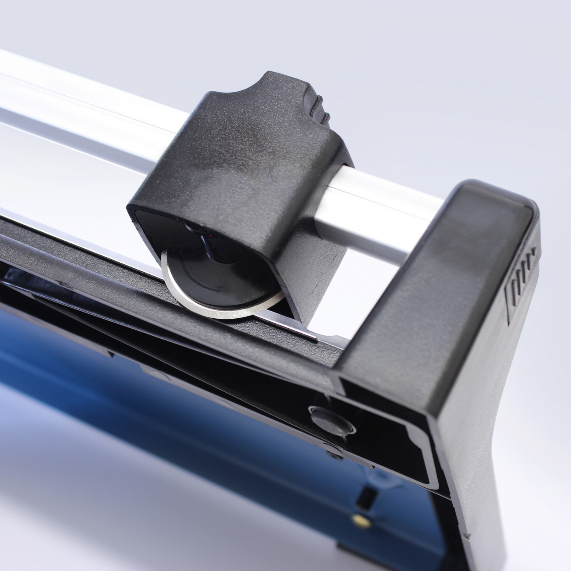 A close view of the cutting head on an A3 rotary paper trimmer, featuring a textured black handle for a secure grip and the round blade that ensures clean cuts, with a glimpse of the blue metal base for stability.