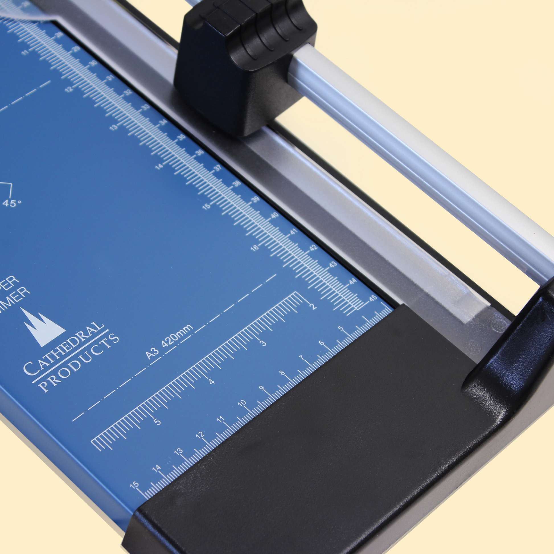 Zoomed-in view of the measurement details on the blue metal base of a Cathedral Products A3 rotary paper trimmer, highlighting the precise calibration for various paper sizes and angled cuts.