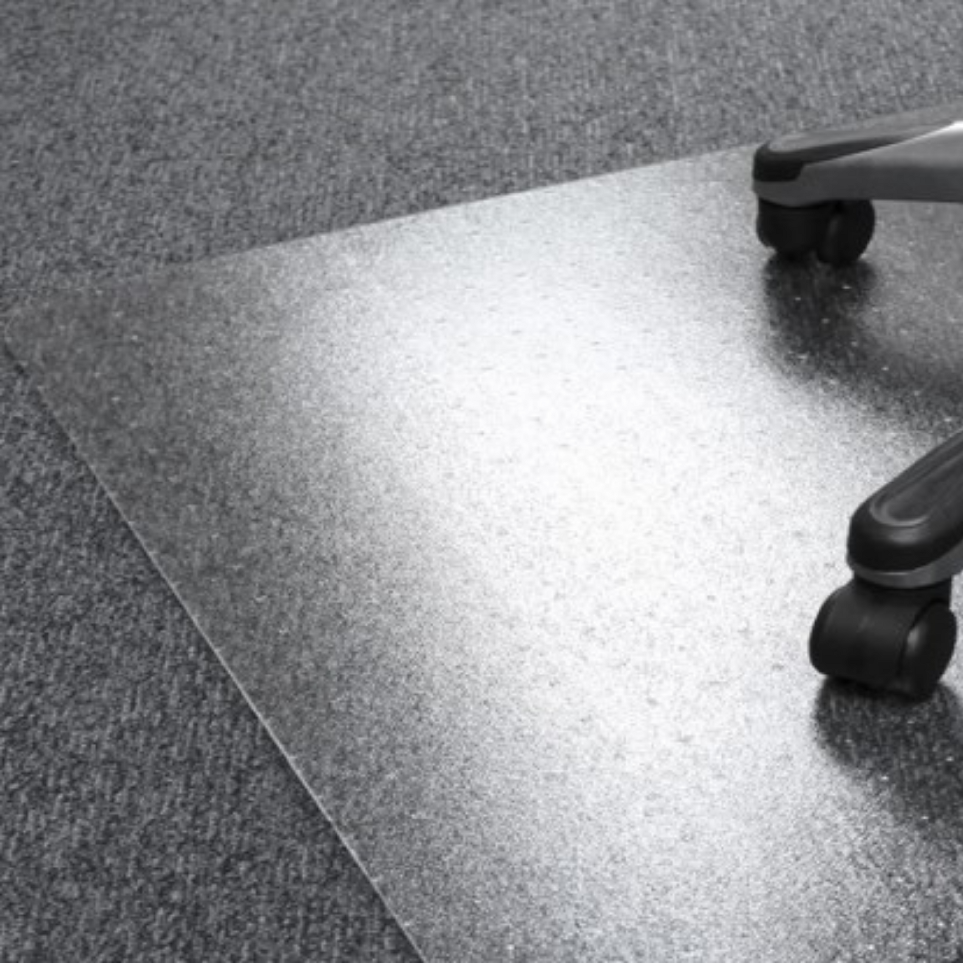 A translucent PVC floor mat designed for low pile carpets, sized 90x120cm, is partially visible under the wheels of an office chair, offering floor protection and chair mobility on carpeted surfaces.