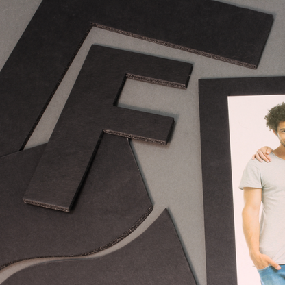 Creative display of cut-out black 5mm foam board pieces, featuring an abstract design, and a photo glued onto a square of foamboard, showing the boards many applications and ease of use.