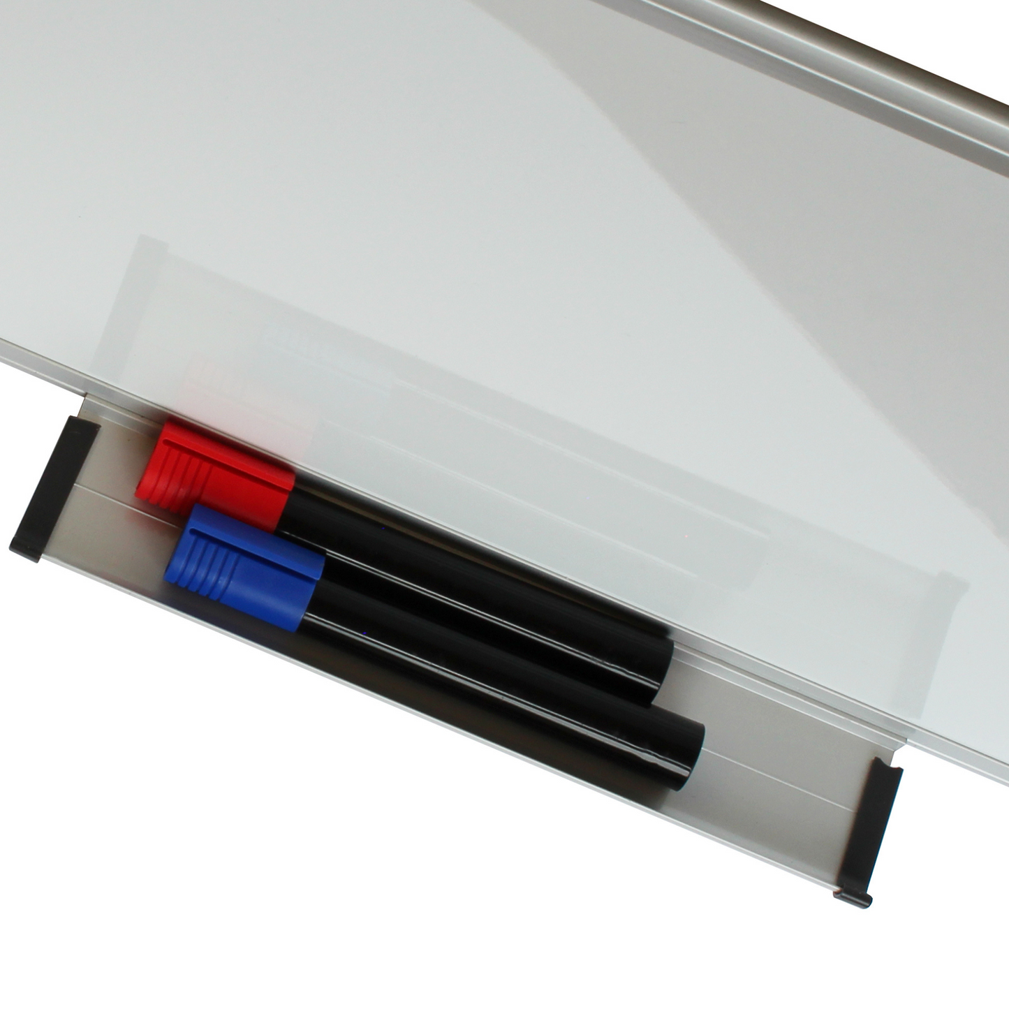 Whiteboard marker tray holding three markers with caps on, colors red, black, and blue (Not included), against a white magnetic board with a metallic frame.