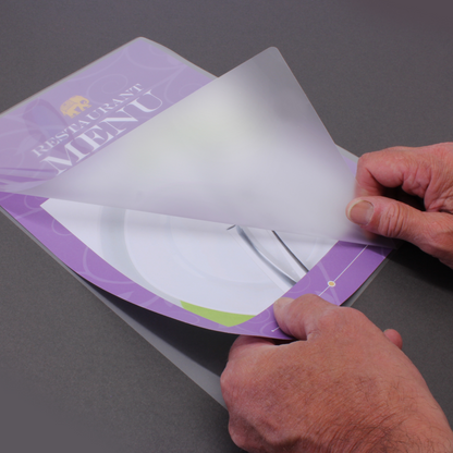 A person's hands peeling open an A5 gloss laminating pouch, 150 micron, with a restaurant menu about to be inserted, depicting the process of preparing items for lamination.