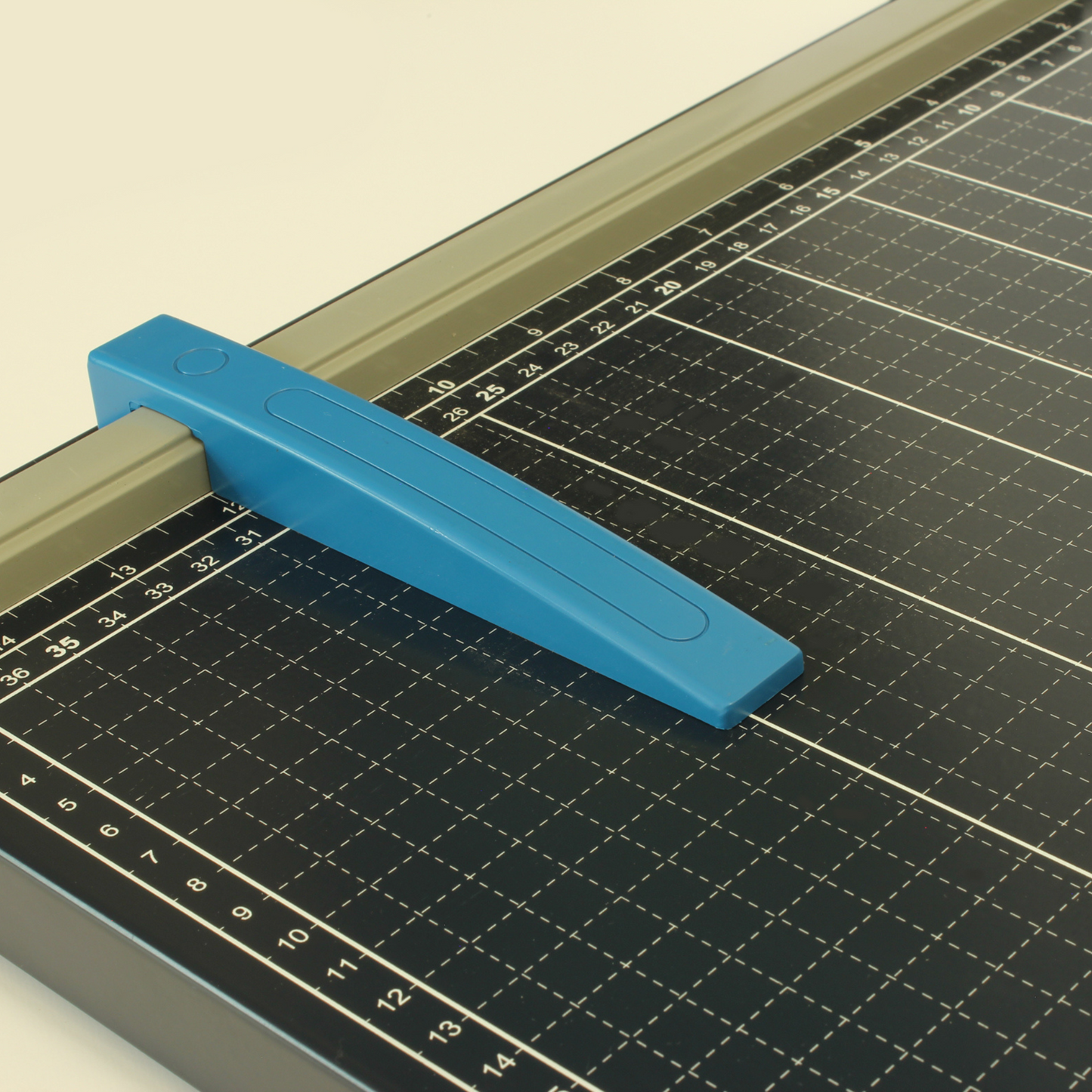 Close-up of the blue paper guide on an A3 paper guillotine cutter, set on a metal base with detailed grid lines and measurement markings, highlighting the tool's precision cutting feature.