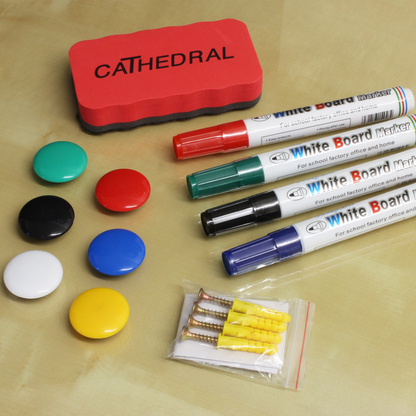 included whiteboard accessories, comprising of 6 multicoloured round magnets, dry erase markers in green, red, blue and black, as well as a whiteboard eraser, with Cathedral Products branding, and a pack of screws and wall plugs for wall mounting the board. These are  displayed on a wooden desk.