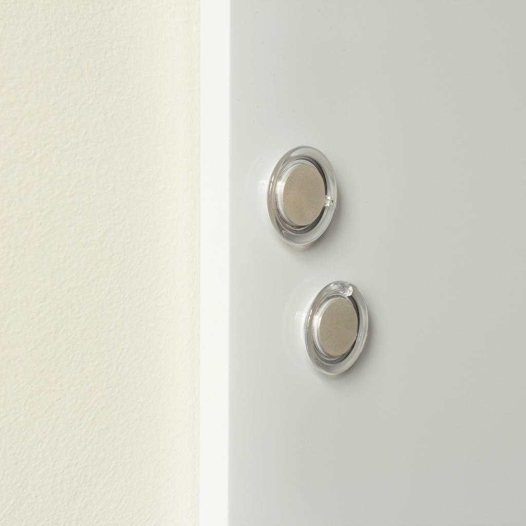 Two round, transparent magnets on a frameless white dry-erase board, highlighting the board's magnetic feature that allows for attaching notes or documents. The simple and clean design is suitable for a variety of settings, from kitchens to offices.