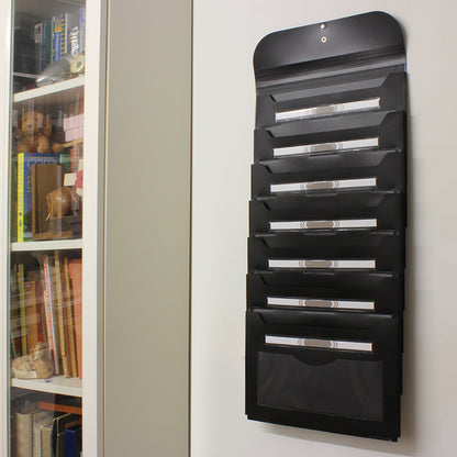 An empty black wall-mounted Wallfile organizer beside a bookshelf, seamlessly integrating into an organized office environment.