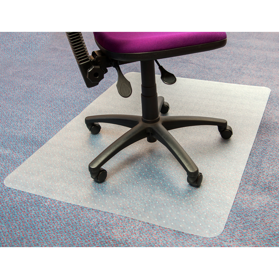 A clear PVC chair mat measuring 90x120cm lies on a multicolored low pile carpet, with a dark purple office chair positioned on top, designed to facilitate smooth chair movement and protect the carpet underneath.
