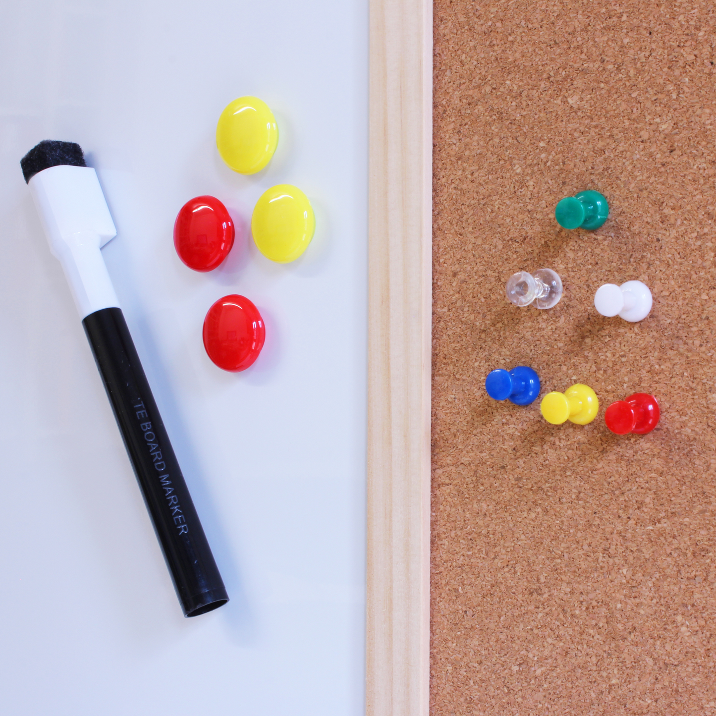 Close-up of a 60x80cm dry erase and cork combination noticeboard, featuring a whiteboard marker and colorful magnets on the white side, with assorted transparent and colored pushpins on the cork side, all framed in natural wood.