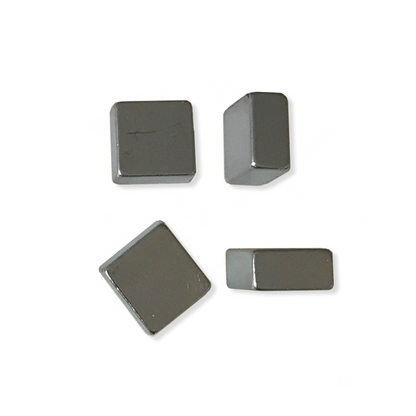 Four designer square neodymium magnets with a metallic finish are scattered on a white background, two are standing on their side, two are lying flat, showing their shaoe and sleek design.